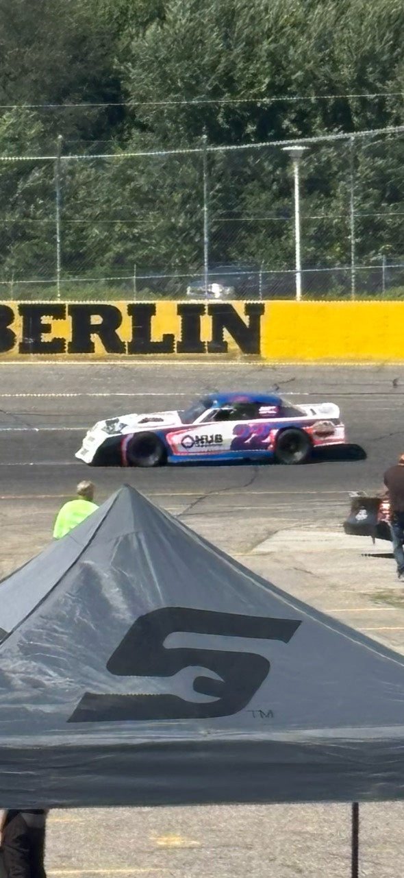 Number 22 passing the yellow Berlin Raceway wall, photographed from the stands