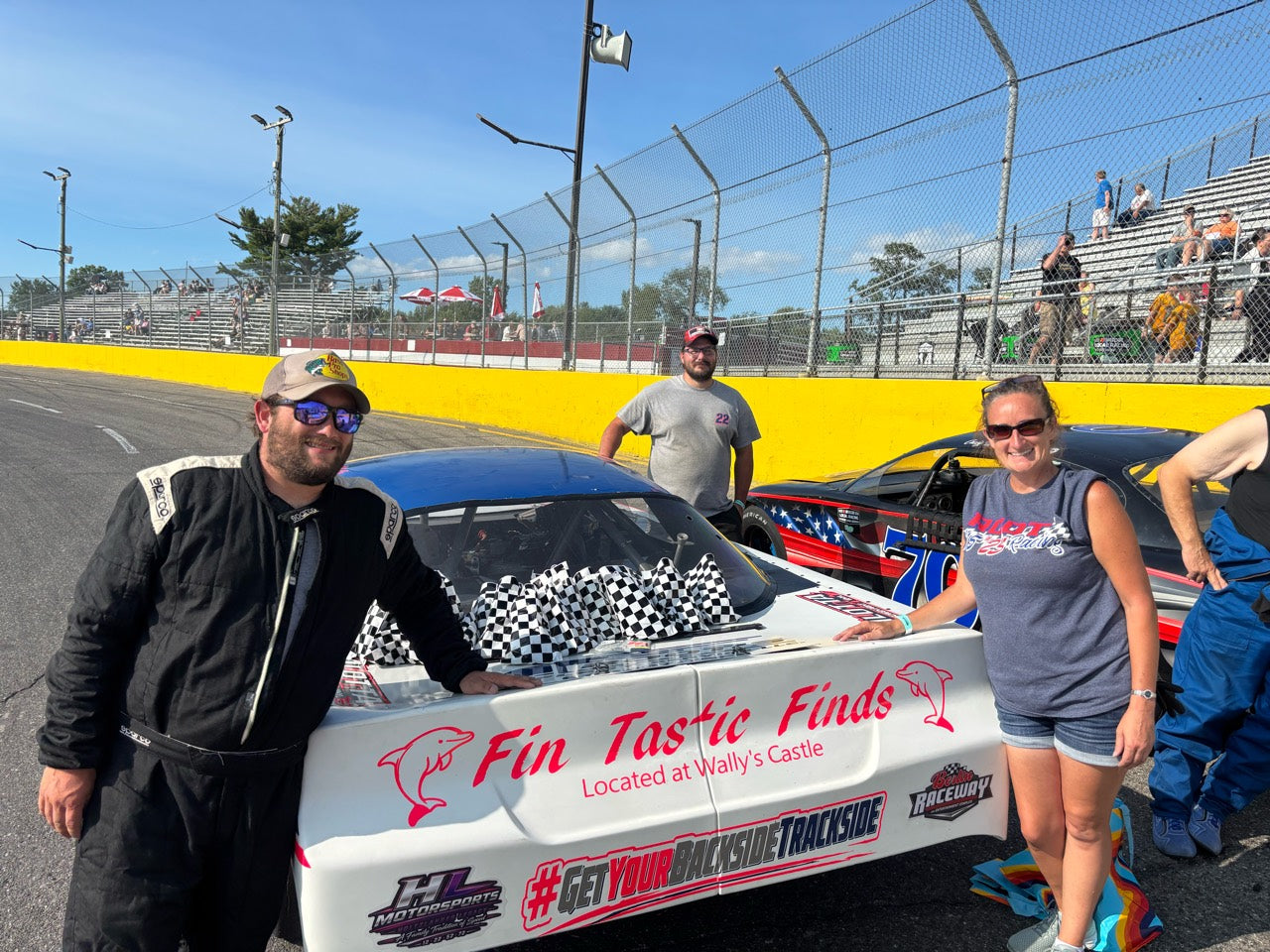 People beside the rear of the HL Motorsports race car with checkered flags on its trunk